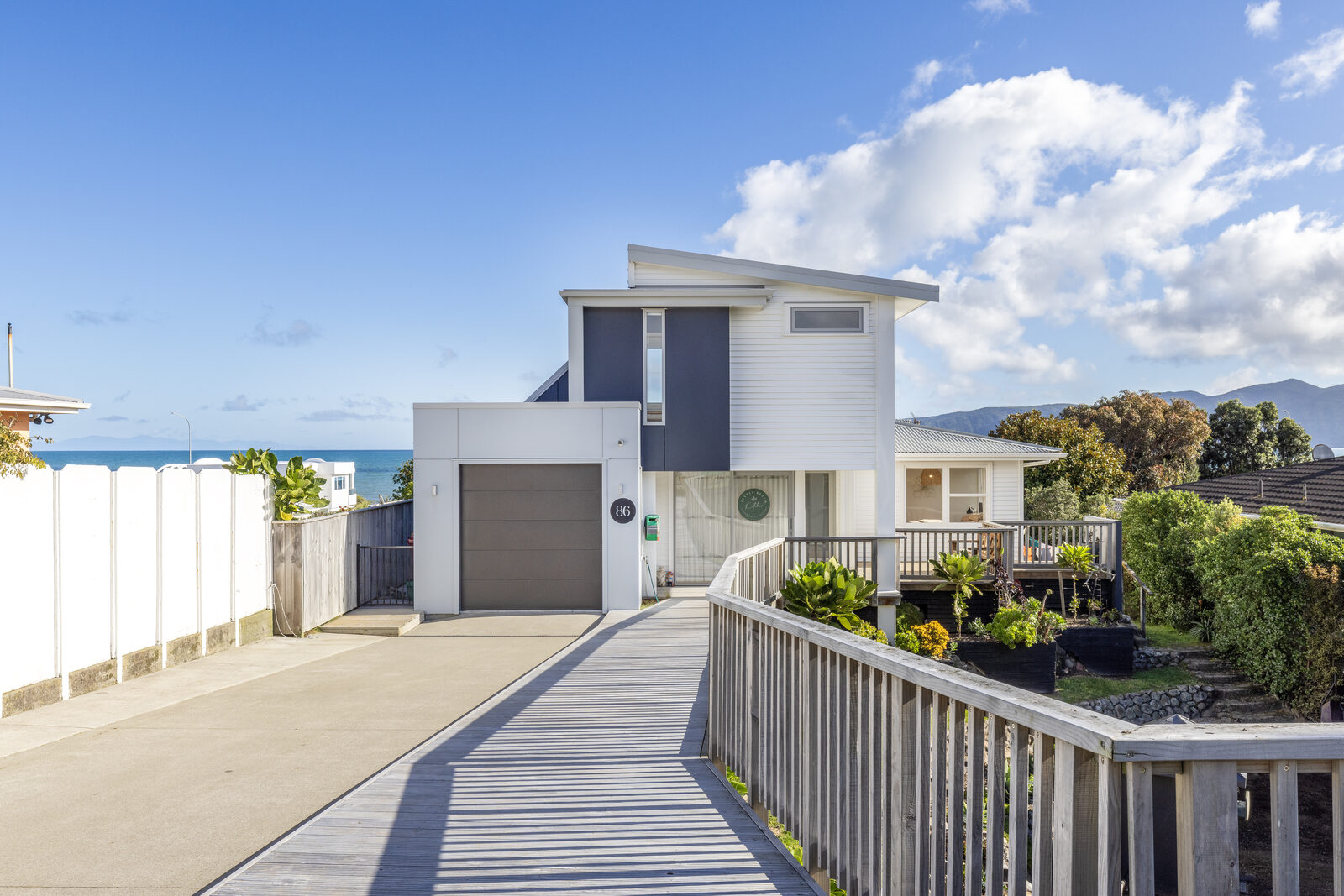 Modern two-storey coastal home with boardwalk approach and sea views