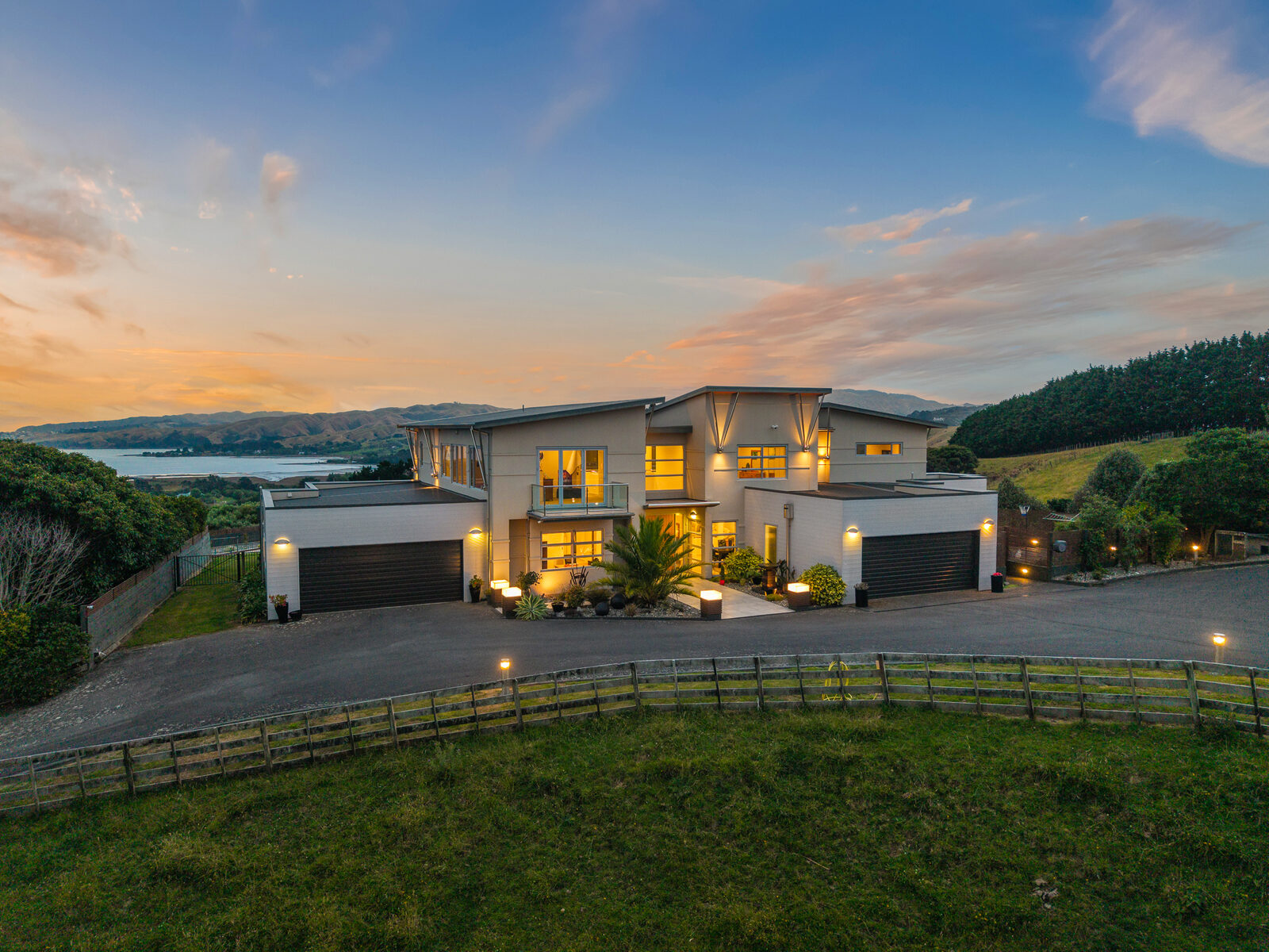 Aerial at twilight, contemporary home with warm interior glow